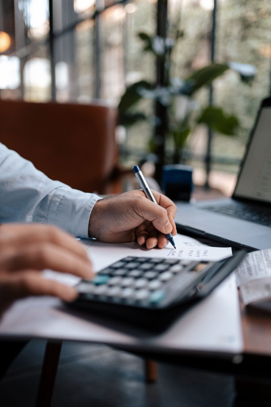Contadora organizando documentos financeiros com calculadora e notebook